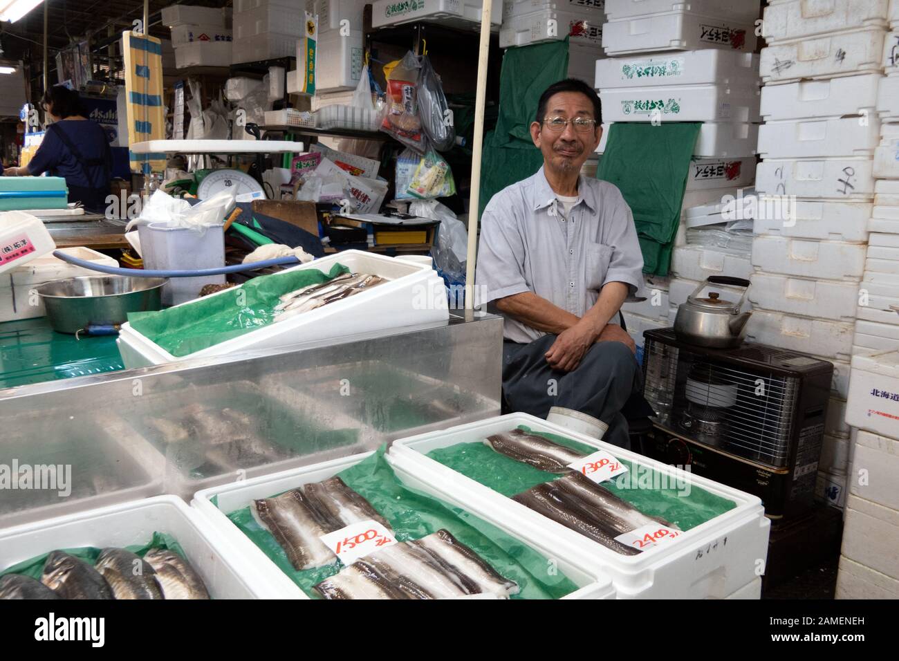Uomo giapponese che guarda la macchina fotografica alla stalla a Shiogama, Prefettura di Miyagi, Giappone, Asia. Negozio che vende pesce fresco al mercato locale del pesce Foto Stock