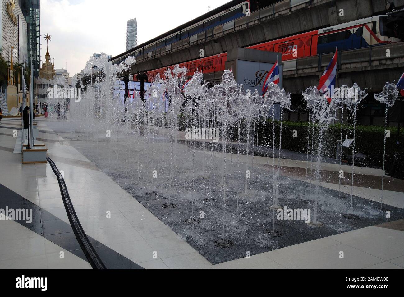Bangkok, Thailandia - 21 dicembre 2019: Fontana tra Siam Center e i centri commerciali Siam Paragon. BTS skytrain treni sullo sfondo. Foto Stock