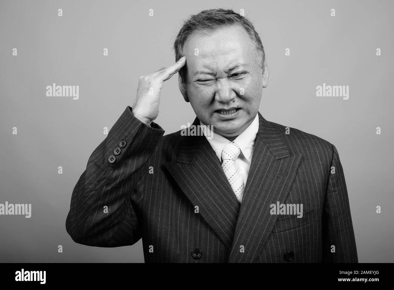 Studio girato di uomo d'affari asiatico maturo su sfondo grigio in bianco e nero Foto Stock