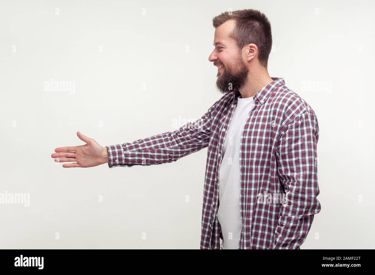 Vista laterale di un amichevole uomo con bearded in camicia casual plaid raggiungere la mano a handshake, familiarizzarsi a colloquio di lavoro, incontrare nuove persone. Indoo Foto Stock