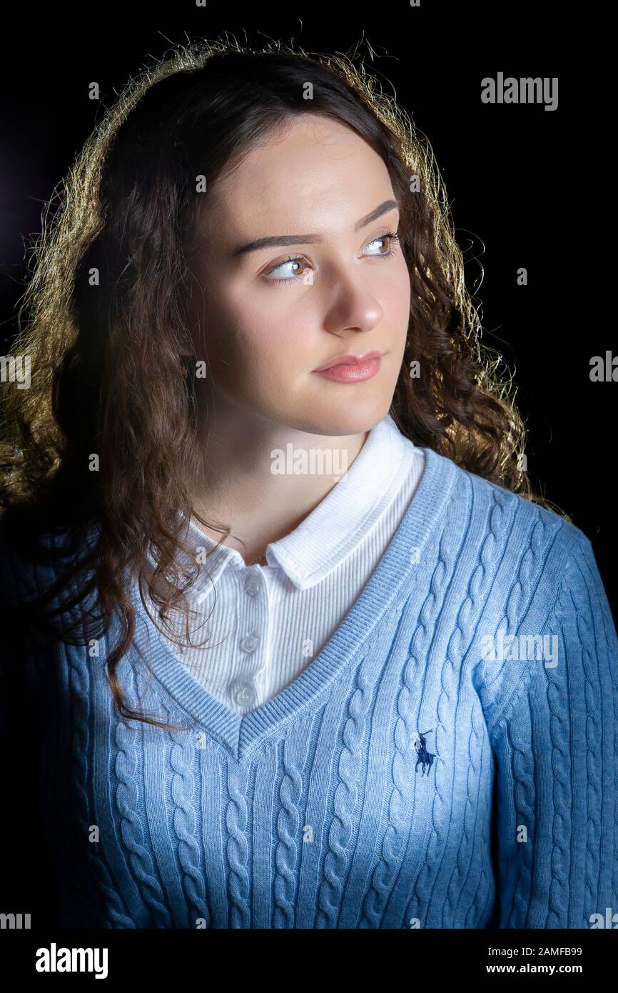 Giovane ragazza che posa per i colpi di studio contro uno sfondo nero, Foto Stock