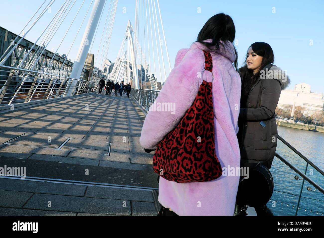 Donna che indossa alla moda lilac pelliccia sintetica cappotto e amico in inverno su Waterloo Footbridge a Londra sud Regno Unito Inghilterra Gran Bretagna KATHY DEWITT Foto Stock