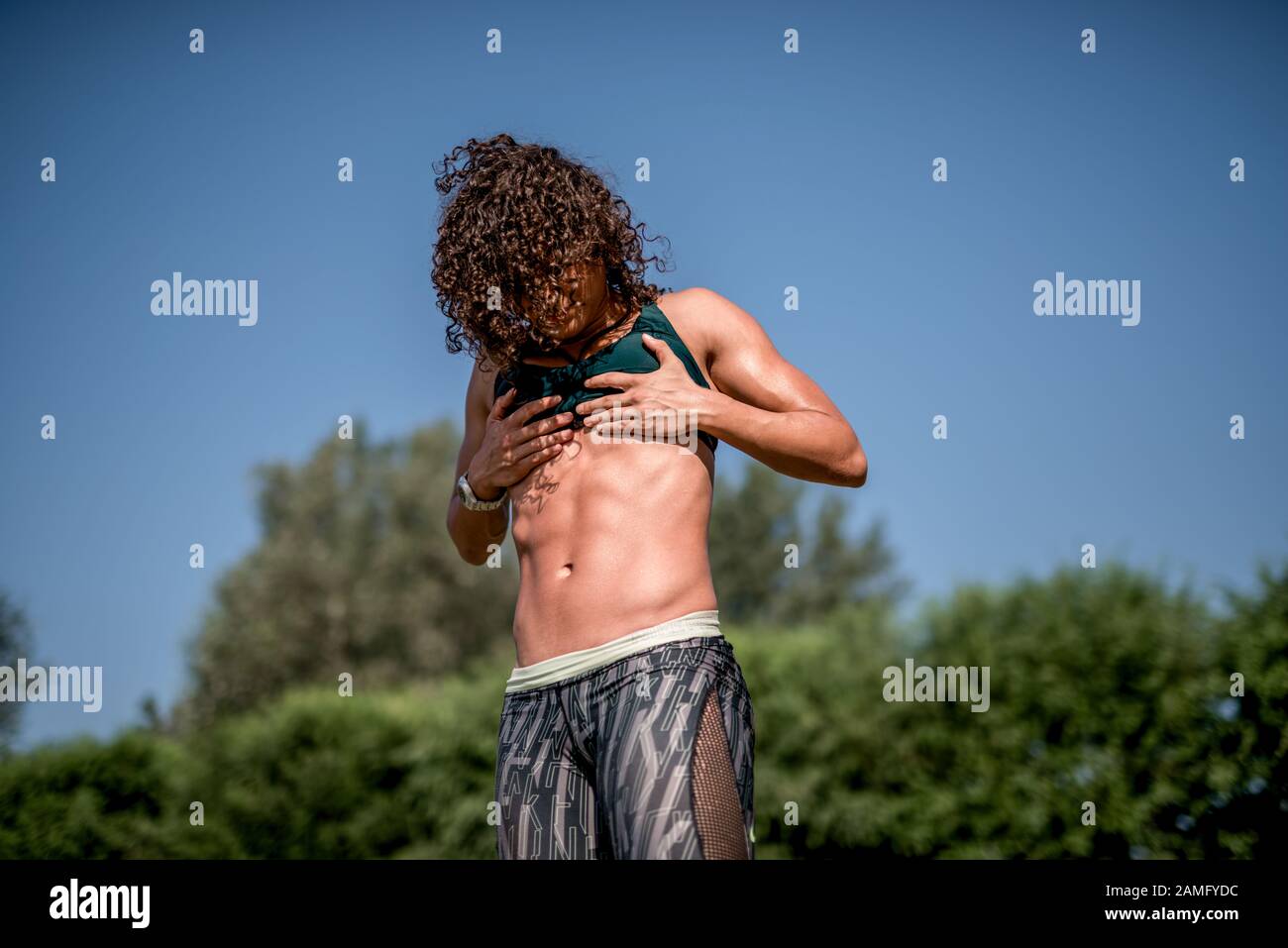 Donna atletica con forti muscoli addominali che posano con le sue mani sui fianchi in luce ombreggiata per enfatizzare il suo fisico Foto Stock