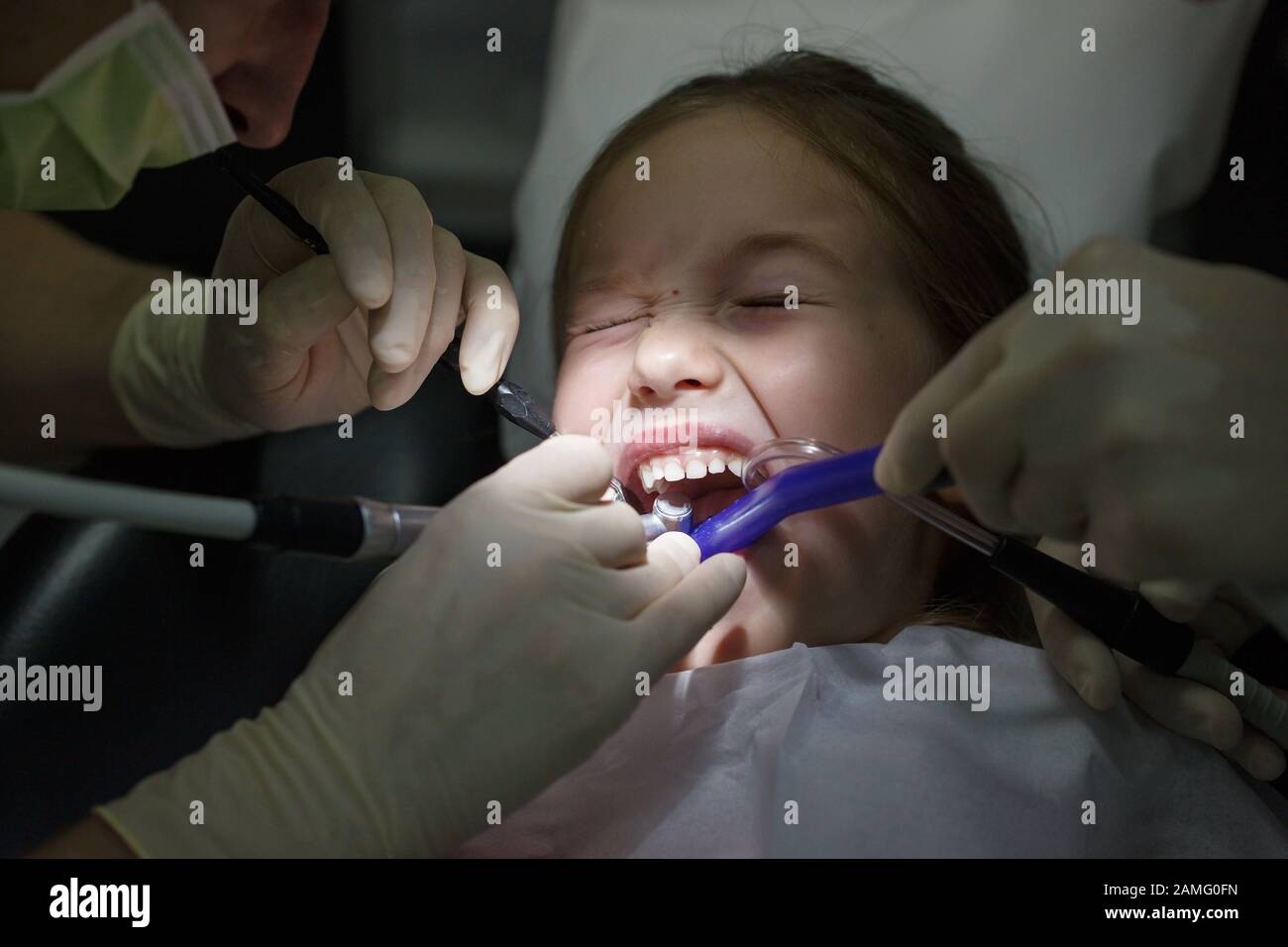 Spaventata bambina presso l ufficio di dentisti, nel dolore durante un checkup. Pazienti pediatrici la cura dentale e la paura del dentista concetto. Foto Stock