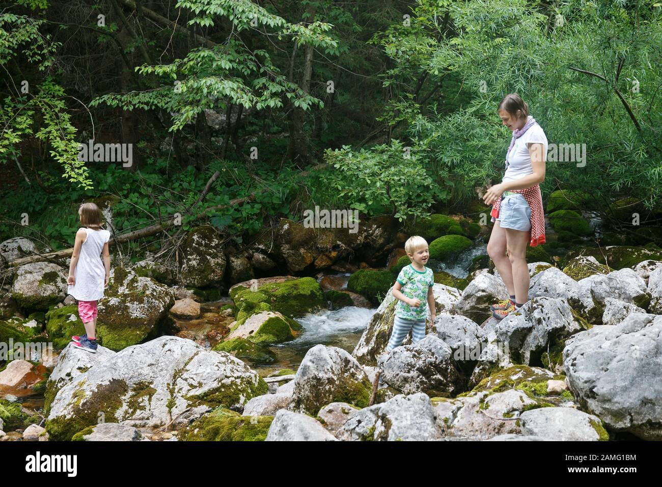 Madre con bambini divertirsi e giocare da un torrente di montagna in estate. Uno stile di vita all'aperto, positivo parenting, infanzia concetto di esperienza. Foto Stock