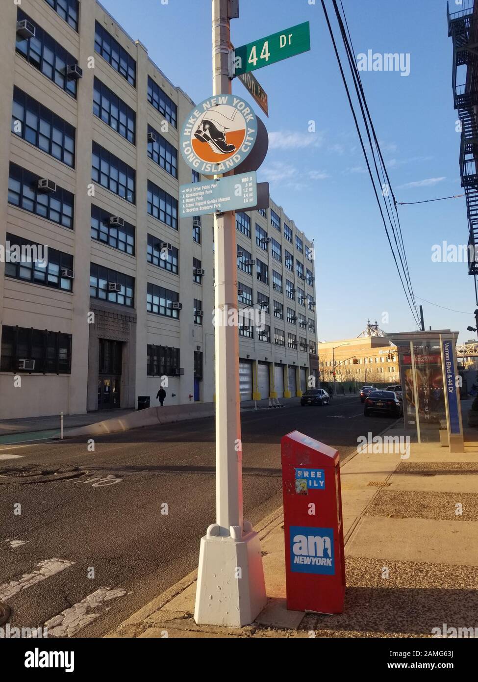 Angolo tra 44th Drive e Vernon Boulevard a Long Island City, Queens, 11 marzo 2019. All'angolo c'è la scatola dei giornali e la fermata dell'autobus di New York. 1990s-era segno sul palo della lampada che fa pubblicità al progetto d'arte 'Hike New York Long Island City', con distanze a piedi per le attrazioni locali stampate sotto. Di fronte all'edificio didattico di New York, presso il 44-36 Vernon Blvd, con una facciata dell'era 1930s "City of New York, Dept of Purchase, Bureau of Stores". () Foto Stock