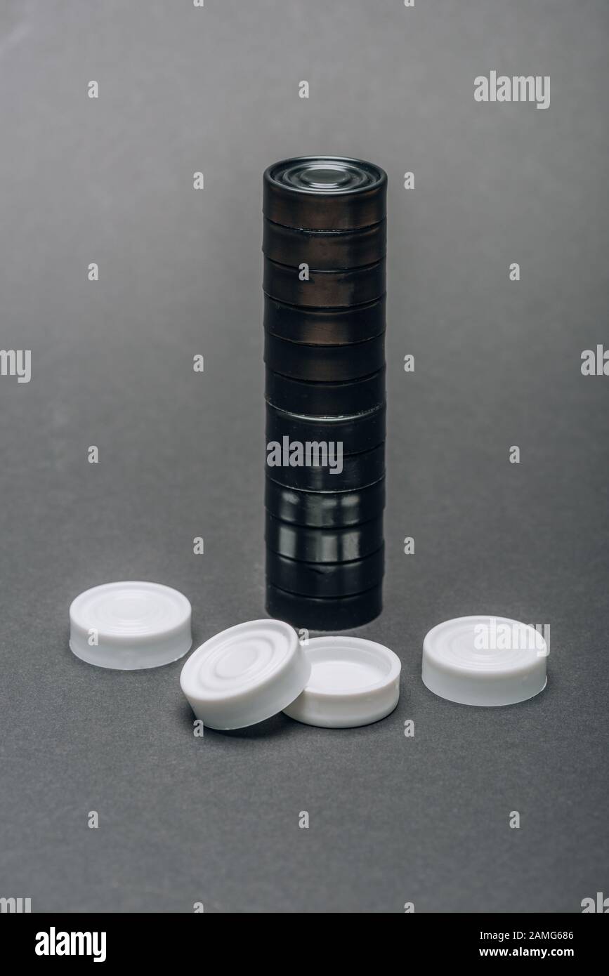 Pedine bianche e nere su sfondo grigio Foto Stock