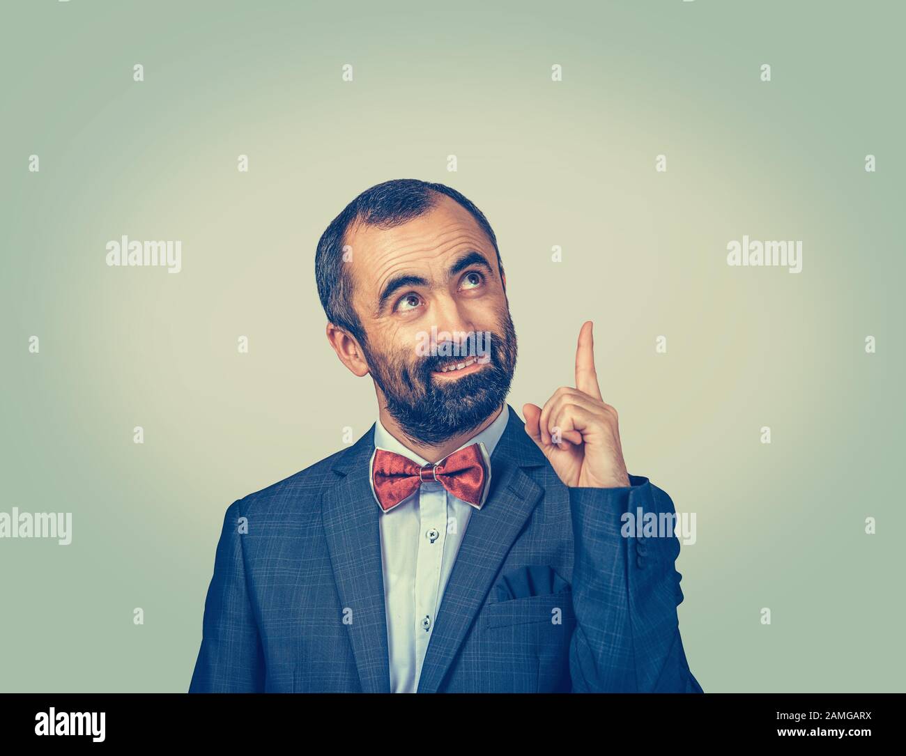 Uomo elegante e bearded che ha idea che punta con il dito indice e che guarda verso l'alto isolato su sfondo giallo chiaro. Gesto viso expresssi Foto Stock