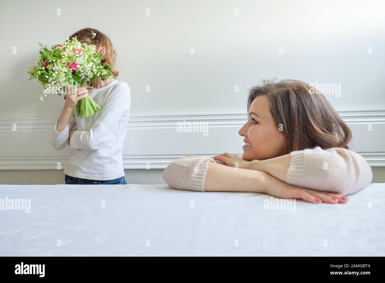 Foto emotiva della madre e figlia, ragazza con bouquet di fiori il viso coperto Foto Stock