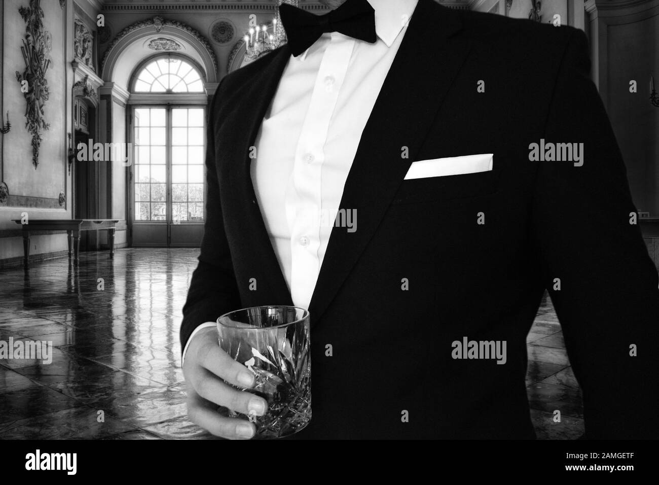 Una vista ravvicinata di un uomo in un tuxedo nero che tiene un bicchiere di whisky in un palazzo. Ideale per un evento a tema con cravatta nera come la residenza gatsbys Foto Stock Una vista ravvicinata di un uomo in un tuxedo nero che tiene un bicchiere di whisky in un palazzo. Ideale per un evento a tema con cravatta nera come la residenza gatsbys Foto Stock