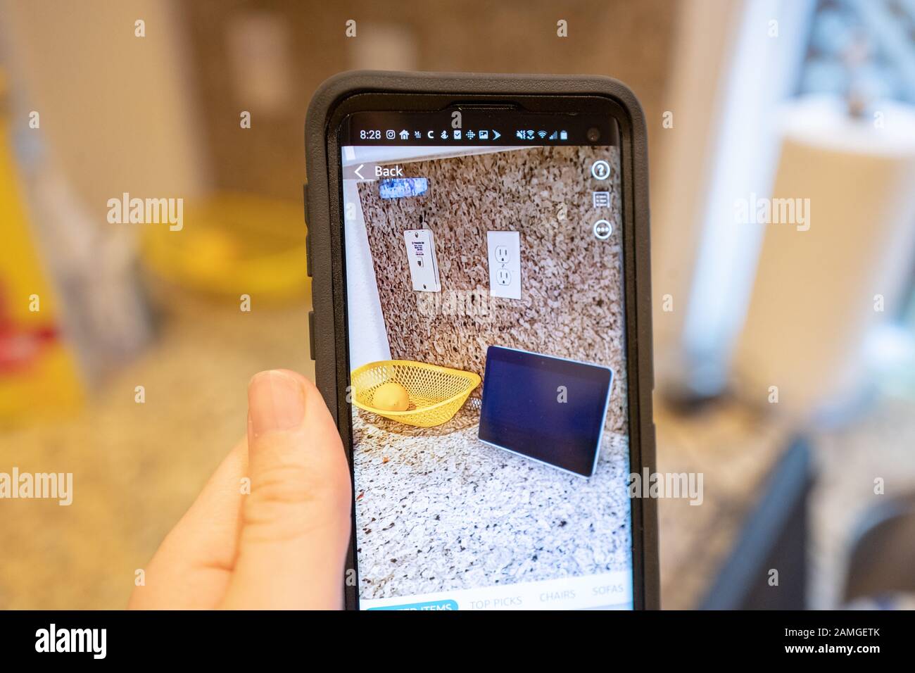 Mano di un uomo che tiene uno smartphone e utilizza le funzionalità di Realtà aumentata nell'app per lo shopping Amazon per visualizzare un dispositivo Amazon Echo Show su un bancone della cucina, San Ramon, California, 22 novembre 2019. La AR viene sempre più utilizzata come caratteristica per i consumatori per visualizzare i prodotti nelle loro case prima di prendere una decisione di acquisto. () Foto Stock
