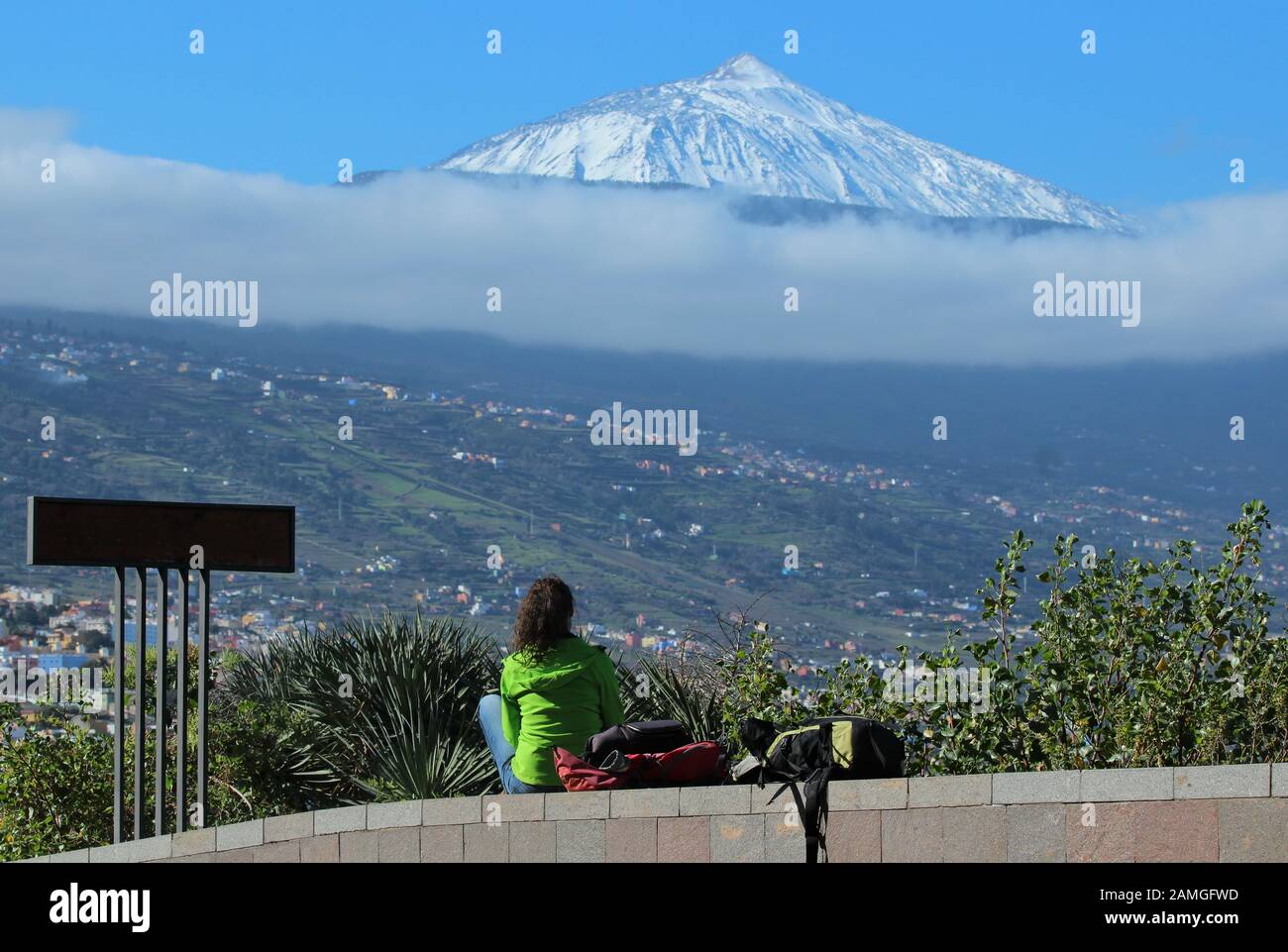 La giovane donna guarda dal Mirador de Humbold al vulcano innevato Teide a Tenerife e sopra la valle di Orotava Foto Stock