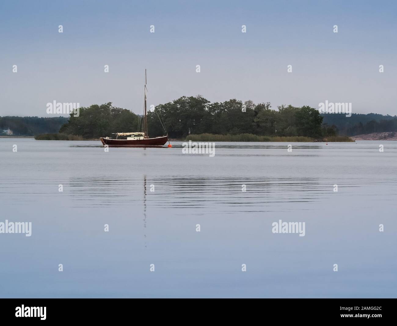 Barca a vela pacificamente ancorata nel tranquillo Mar Baltico vicino Godby, Aland, Finlandia Foto Stock