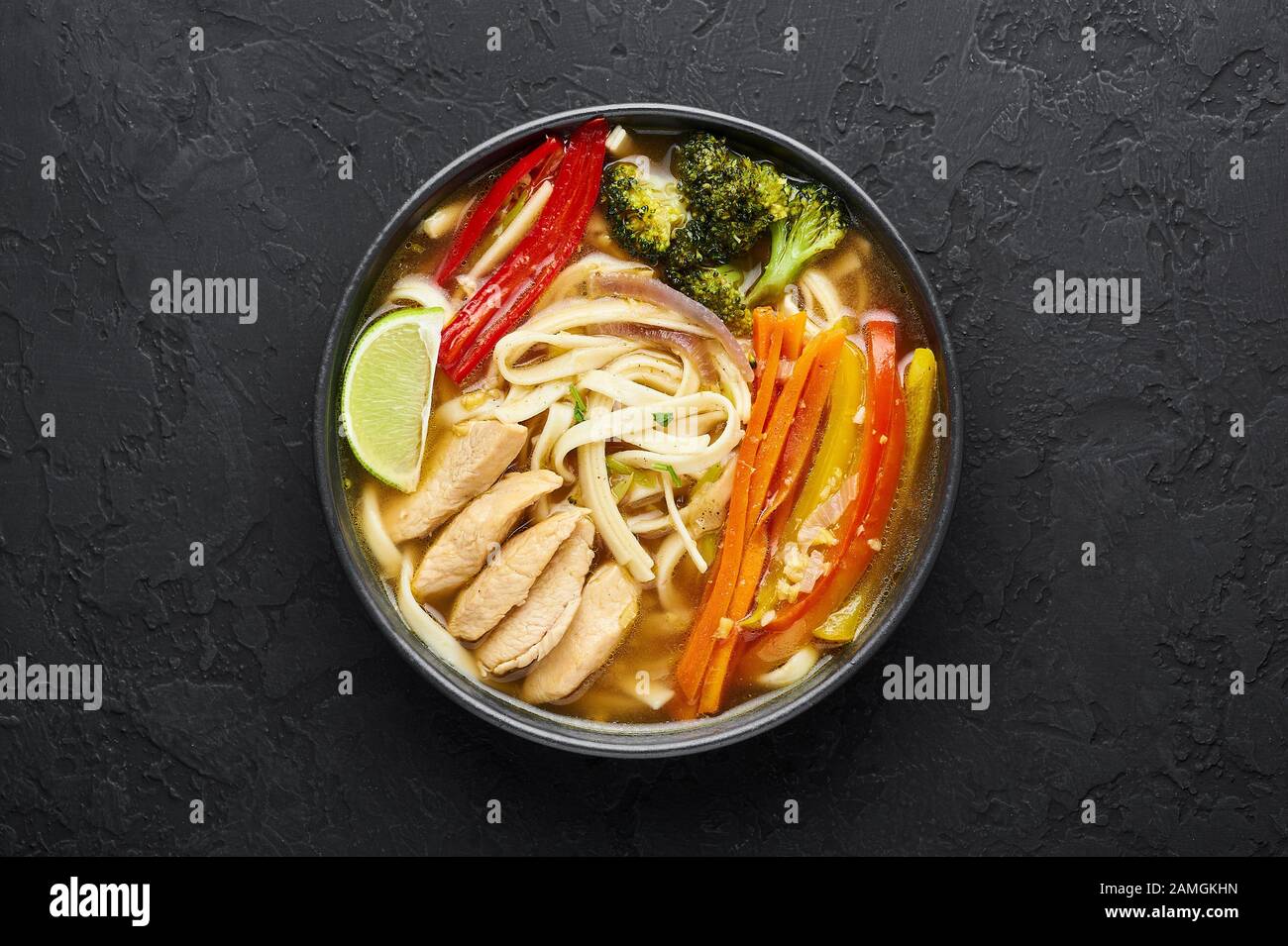 Pollo Thukpa in ciotola nera su fondo scuro di ardesia. Il pollo Thukpa è una zuppa di noodle di cucina tibetana con verdure e carne di pollo. Vista dall'alto Foto Stock