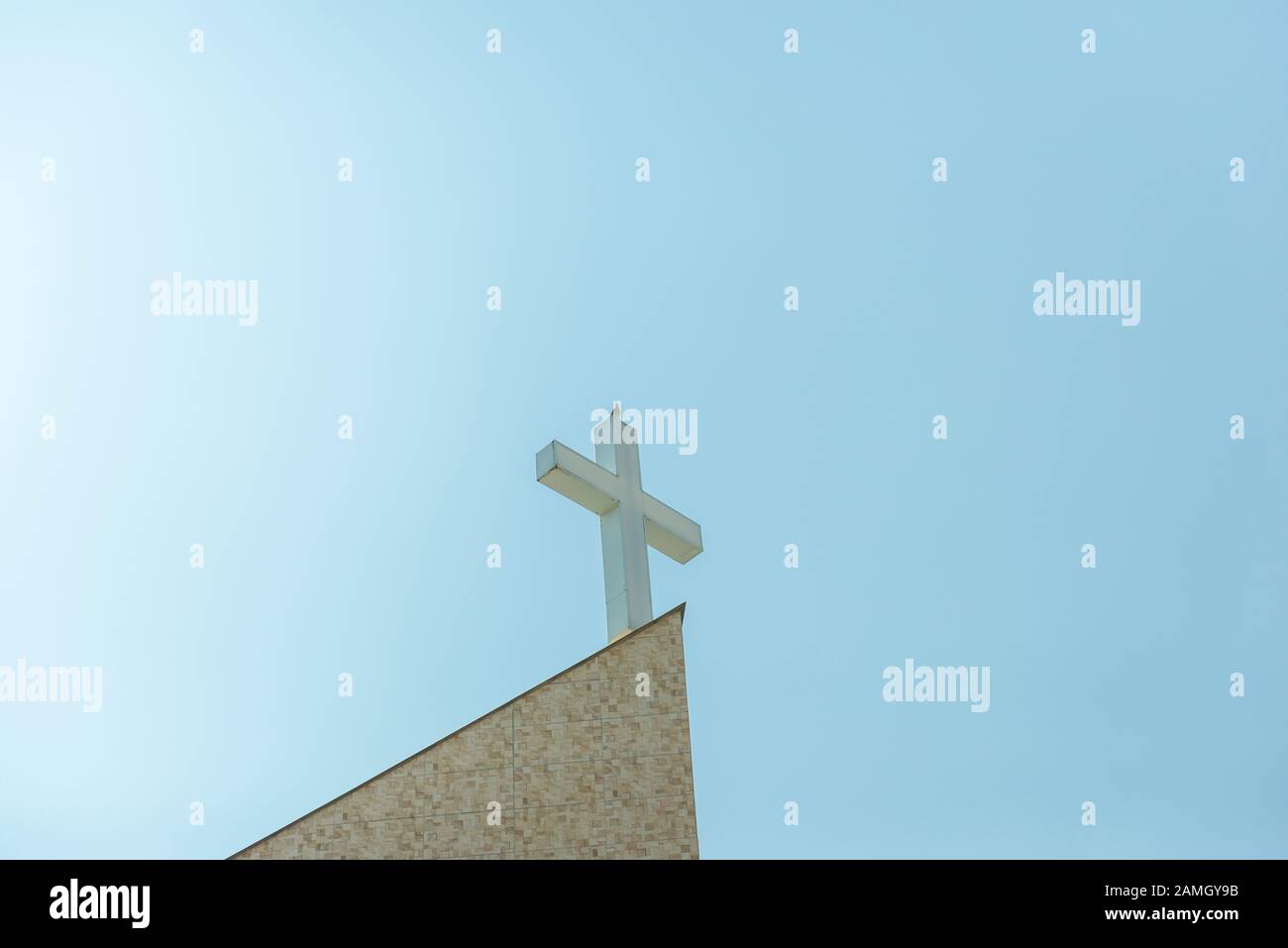 Colomba volare sopra una croce cristiana nella chiesa cattolica su uno sfondo blu cielo. Concetto di fede, di pace e di religione. Vista dal basso dalla croce della chiesa Foto Stock