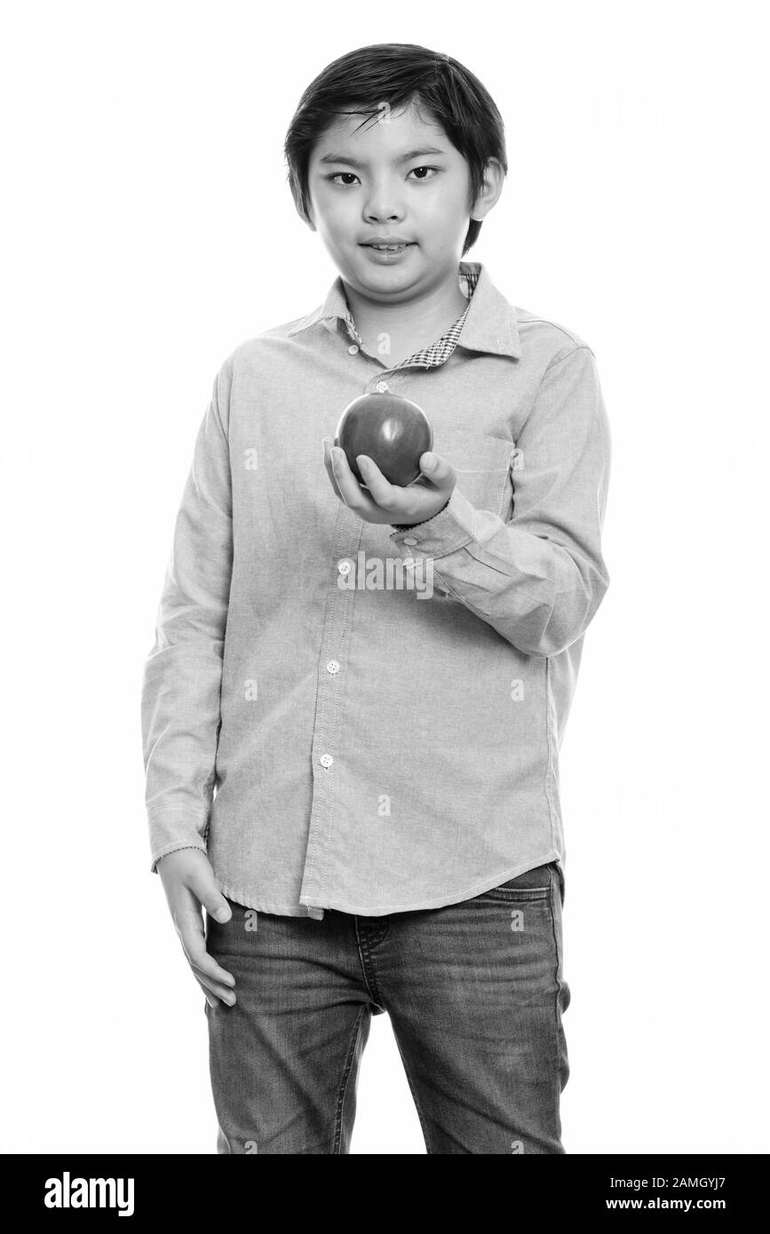 Studio shot di carino ragazzo giapponese in piedi tenendo red apple Foto Stock