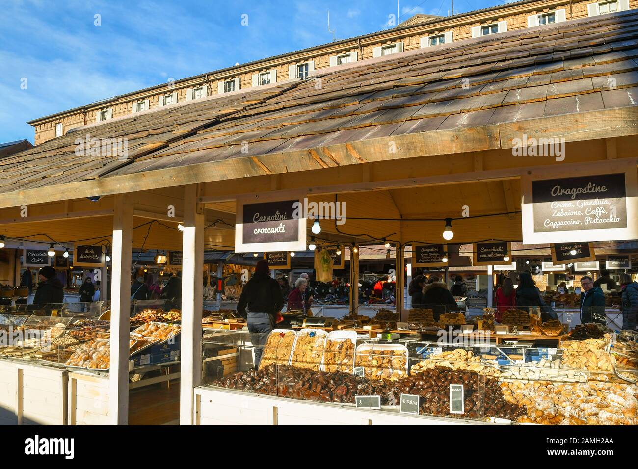 Una tavola che vende fiocchi e prelibatezze al tradizionale mercatino di Natale in Piazza Castello in una soleggiata vigilia di Natale, Torino, Piemonte, Italia Foto Stock