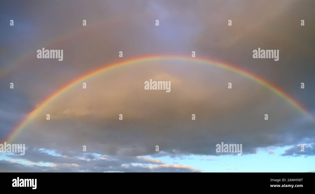 Pieno doppio arcobaleno nel cielo sullo sfondo delle nuvole Foto Stock