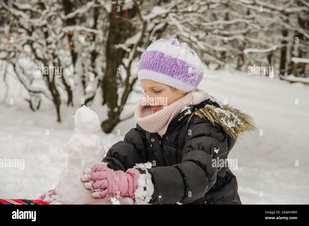 adorabile ragazza divertirsi con lo snowman in neve meraviglia Foto Stock