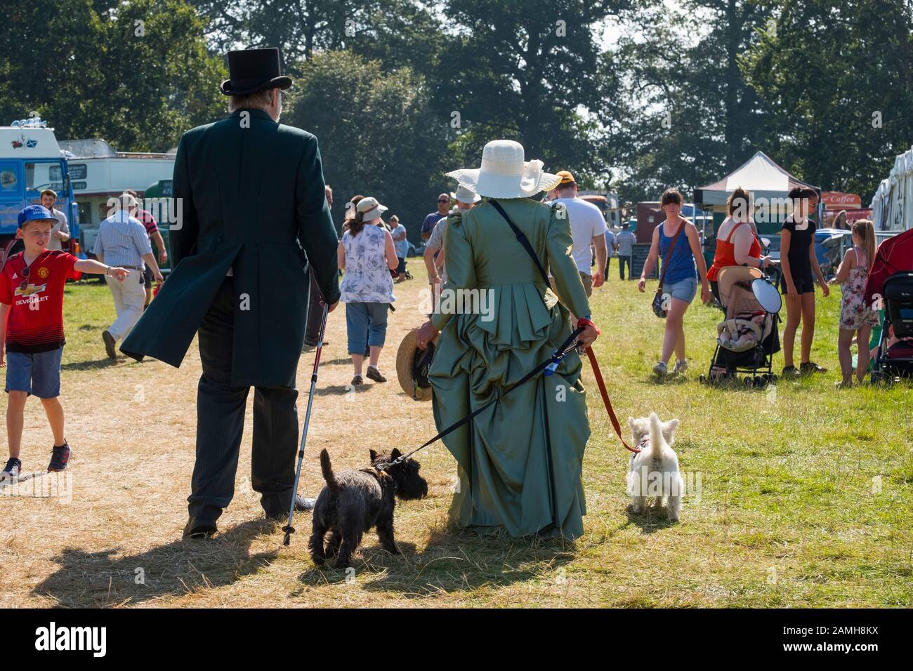 L uomo e la donna in costume a piedi con due cani di 2019 Shrewsbury Rally di vapore, Shropshire, Inghilterra, Regno Unito Foto Stock