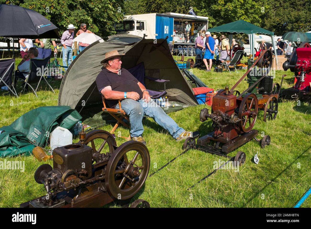Un uomo rilassante circondato da vintage motori stazionari sul display a 2019 Shrewsbury Rally di vapore, Shropshire, Inghilterra, Regno Unito Foto Stock