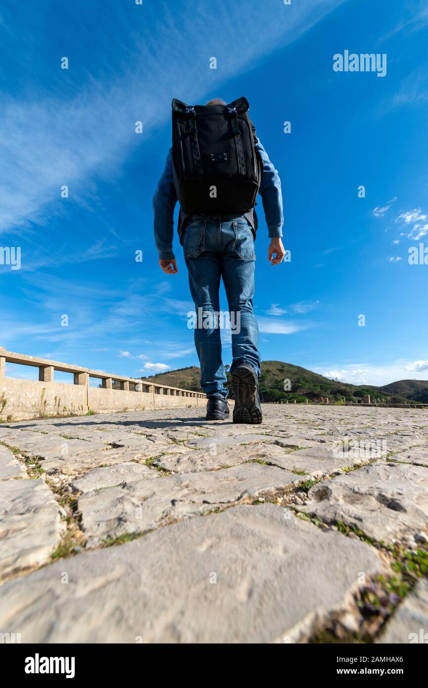 vista posteriore di un uomo che cammina con uno zaino grande Foto Stock