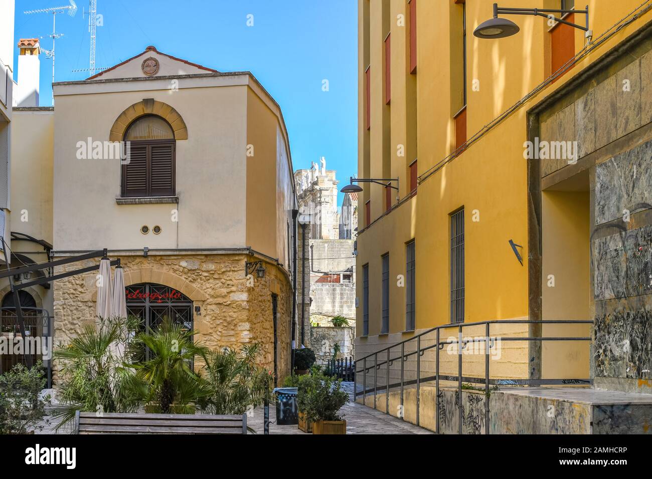 Un piccolo cortile nel centro turistico di Brindisi con le statue del Duomo di Brindisi visibili alle spalle in una giornata di sole nella regione Puglia. Foto Stock