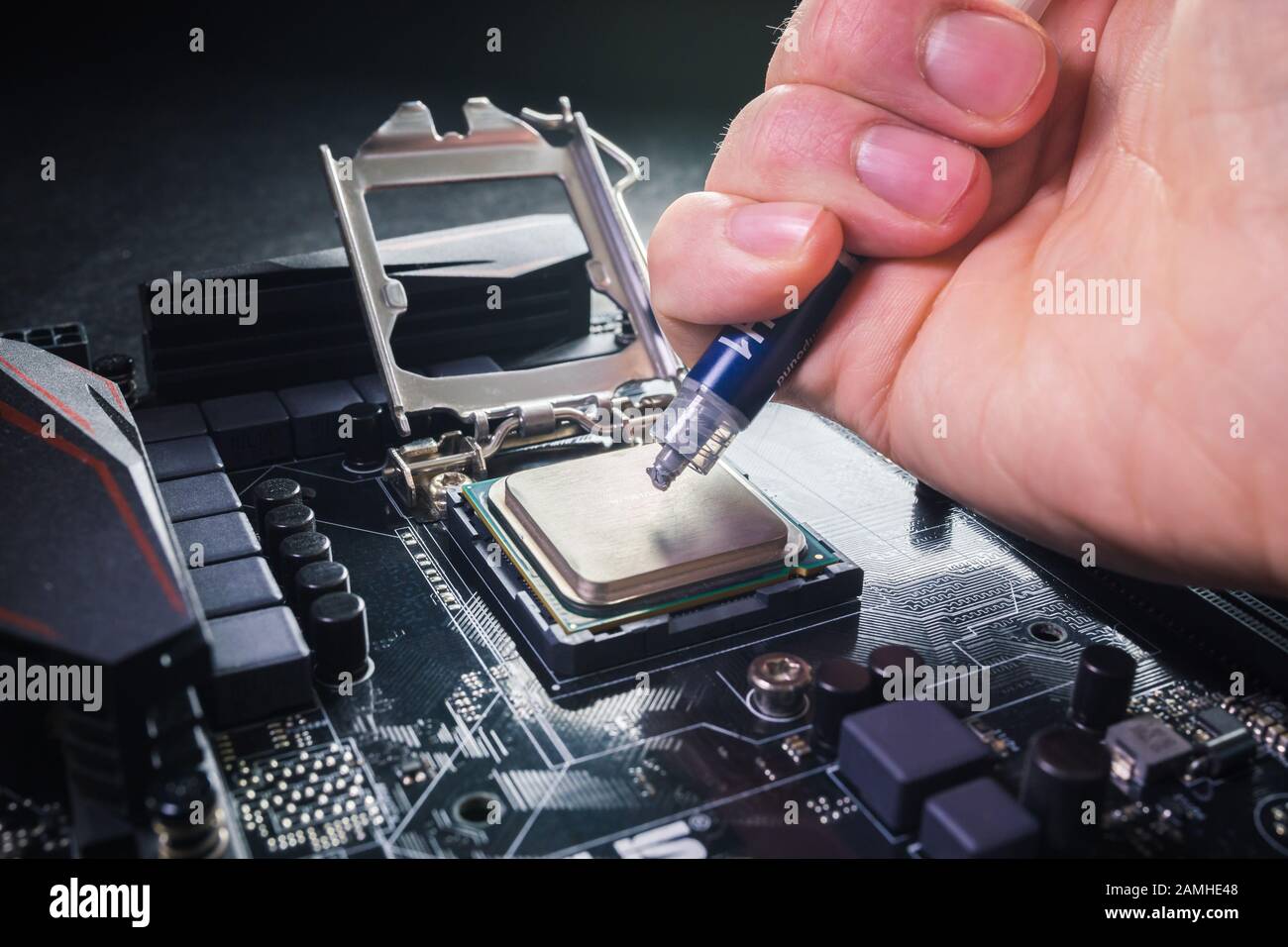 Primo piano per il tecnico che preme o applica il composto di pasta termica sulla parte superiore della cpu principale nel socket. Concetto di riparazione o aggiornamento Foto Stock