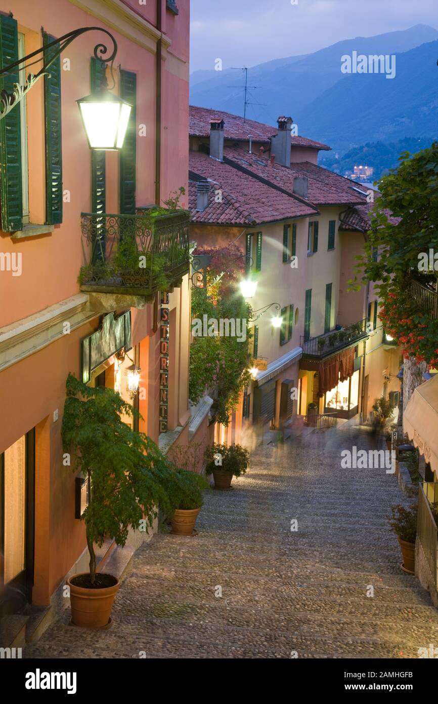 Le lampade illuminano una strada d'atmosfera al tramonto a Bellagio, Lago di Como, Italia. Foto Stock
