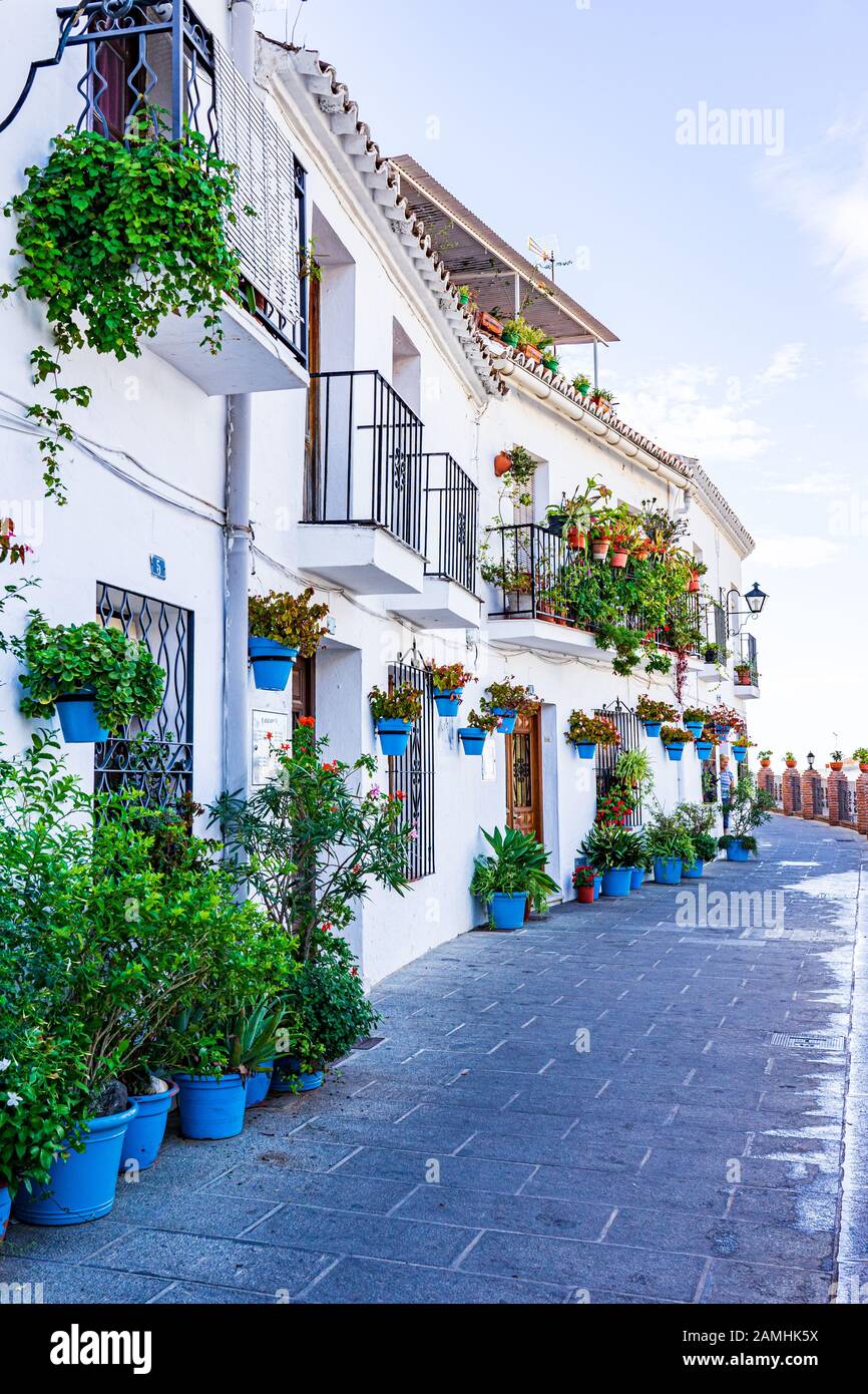 Una pittoresca strada in Mijas, Spagna, dove una varietà di piante sono coltivate in contenitori sul marciapiede fuori il bianco delle case Foto Stock