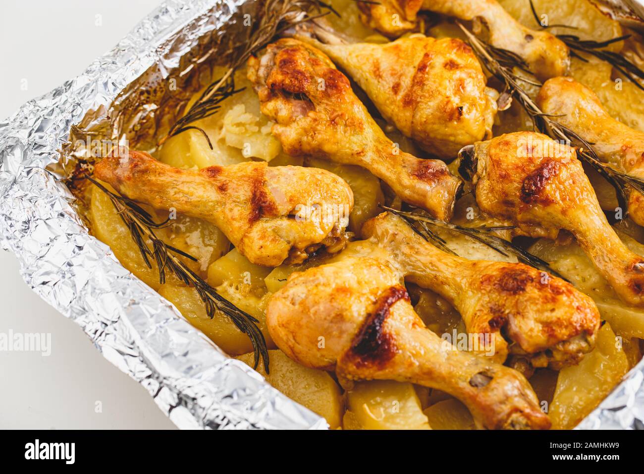 Gambe di pollo appetitose Cotte con Patate e rosmarino In Lamina. Primo piano. Foto Stock