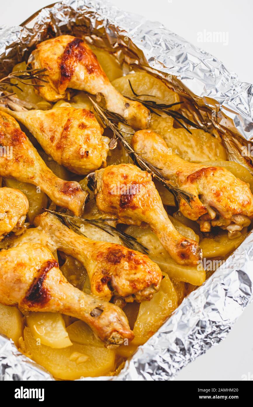 Gambe di pollo appetitose Cotte con Patate e rosmarino In Lamina. Primo piano. Foto Stock