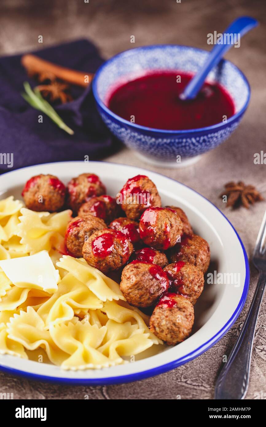Pasta Farfalle con polpette e salsa di mirtilli con spezie ed erbe rosmarino, cannella e anice. Polpette in umido in salsa di bacche dolci. Foto Stock
