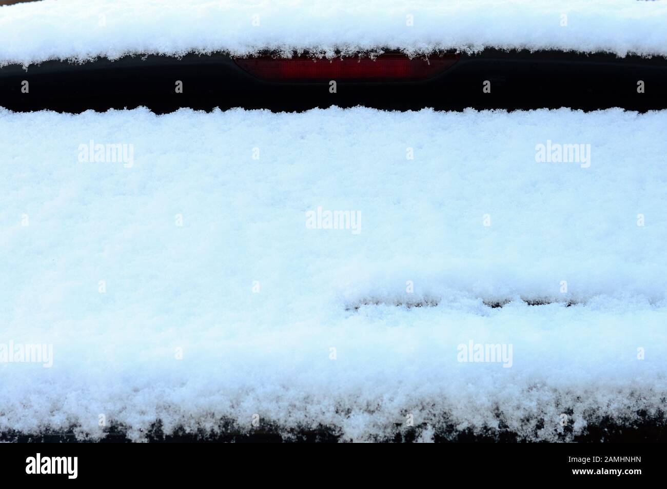 il finestrino posteriore della vettura è coperto di neve dopo una nevicata in una giornata invernale, il traffico è bloccato, il maltempo e le cattive previsioni Foto Stock
