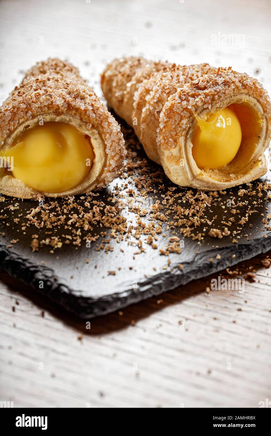 Dolci farciti con crema alla vaniglia su ardesia scura Foto Stock