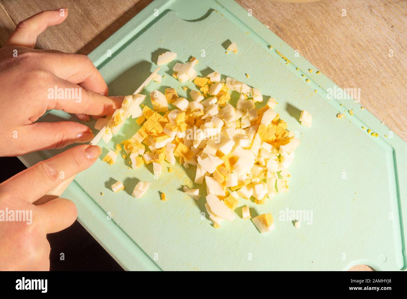 Le mani del cuoco tagliano uova e patate per insalata. Cibo vegetariano sano e naturale Foto Stock