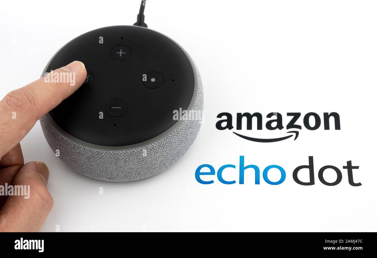 Amazon Echo Dot 3rd generazione, l'utente che interagisce con esso, e il logo stampato su carta. Altoparlante intelligente con assistente Alexa. Foto reale, non un montaggio. Foto Stock
