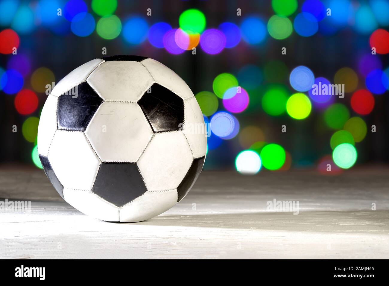 Calcio di calcio su una superficie bianca texture con un'ombra dura su un bokeh colorato di luci il mese di dicembre. Foto Stock