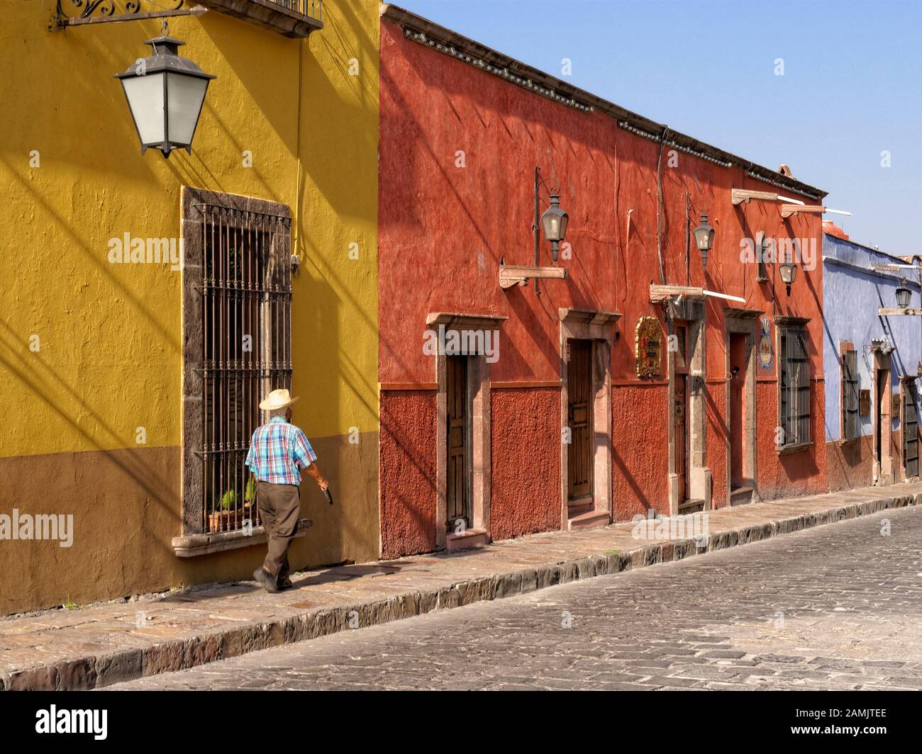 L'uomo messicano cammina davanti alle colorate case coloniali spagnole su Canal Street a San Miguel de Allende, Messico Foto Stock