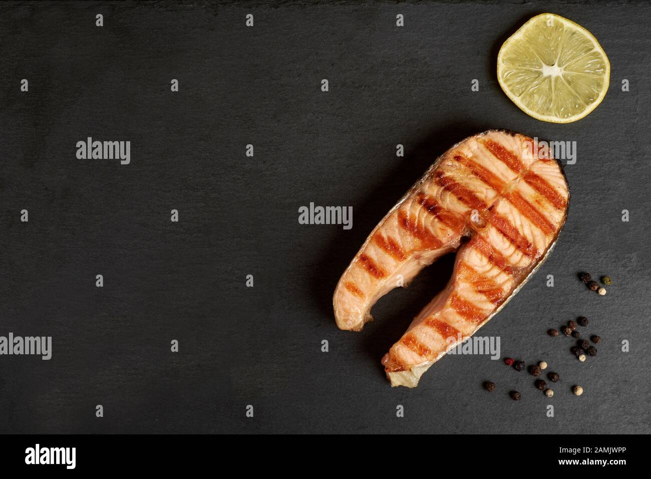 Salmone alla griglia bistecca con un pepe e succo di limone su una piastra di ardesia con spazio di copia Foto Stock