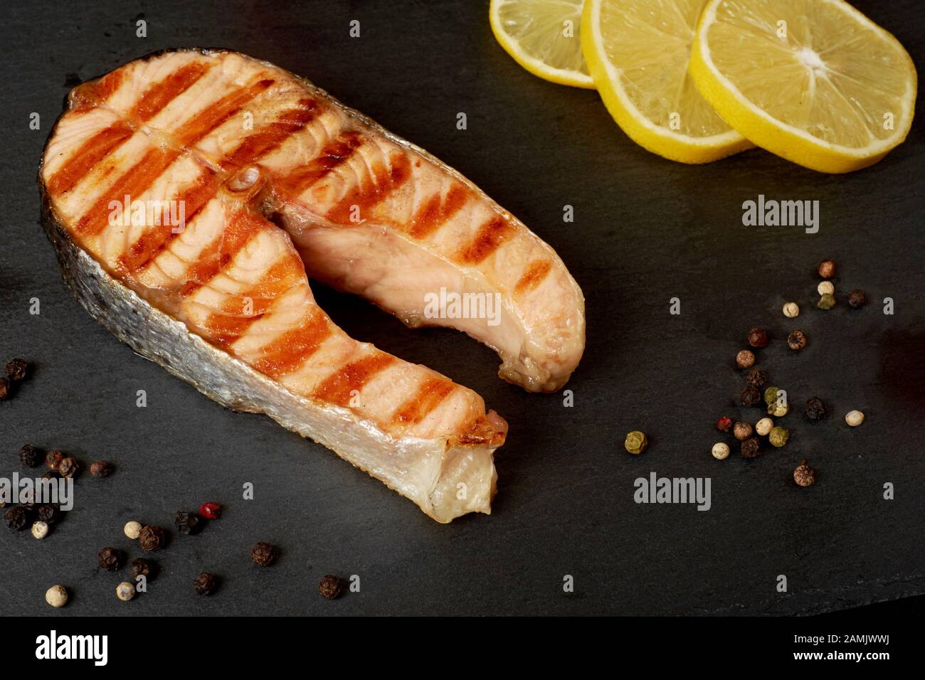 Salmone alla griglia bistecca con un pepe e succo di limone su una piastra di ardesia con spazio di copia Foto Stock