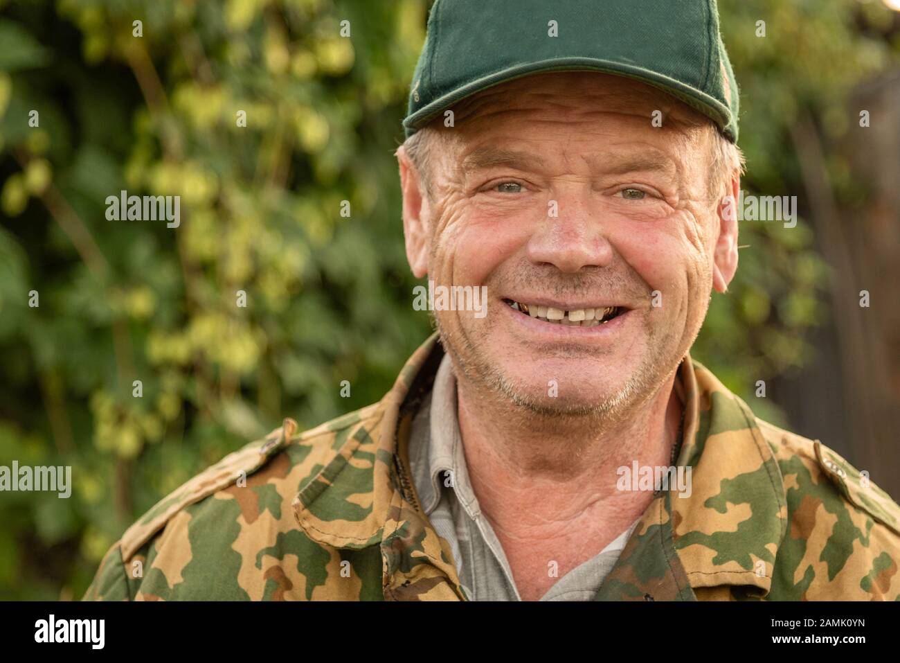 Primo piano ritratto di un uomo russo sorridente che indossa un cappuccio verde e una giacca camouflage . Foto Stock