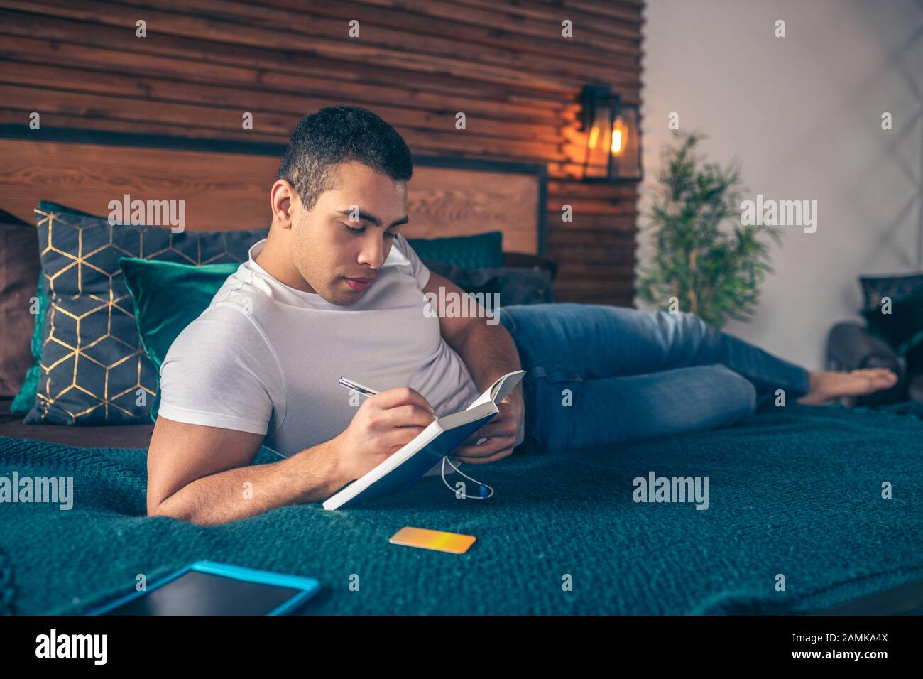 Iscritto ragazzo in un notebook sdraiato su un letto. Foto Stock