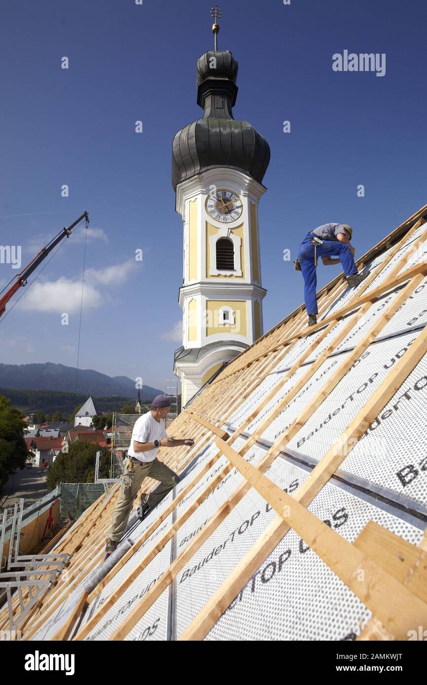 Gli artigiani installano nuove tegole sul traliccio del tetto della Mühlfeldkirche a Bad Tölz. L'ultima volta che il tetto è stato coperto è stato nel 1977. [traduzione automatizzata] Foto Stock