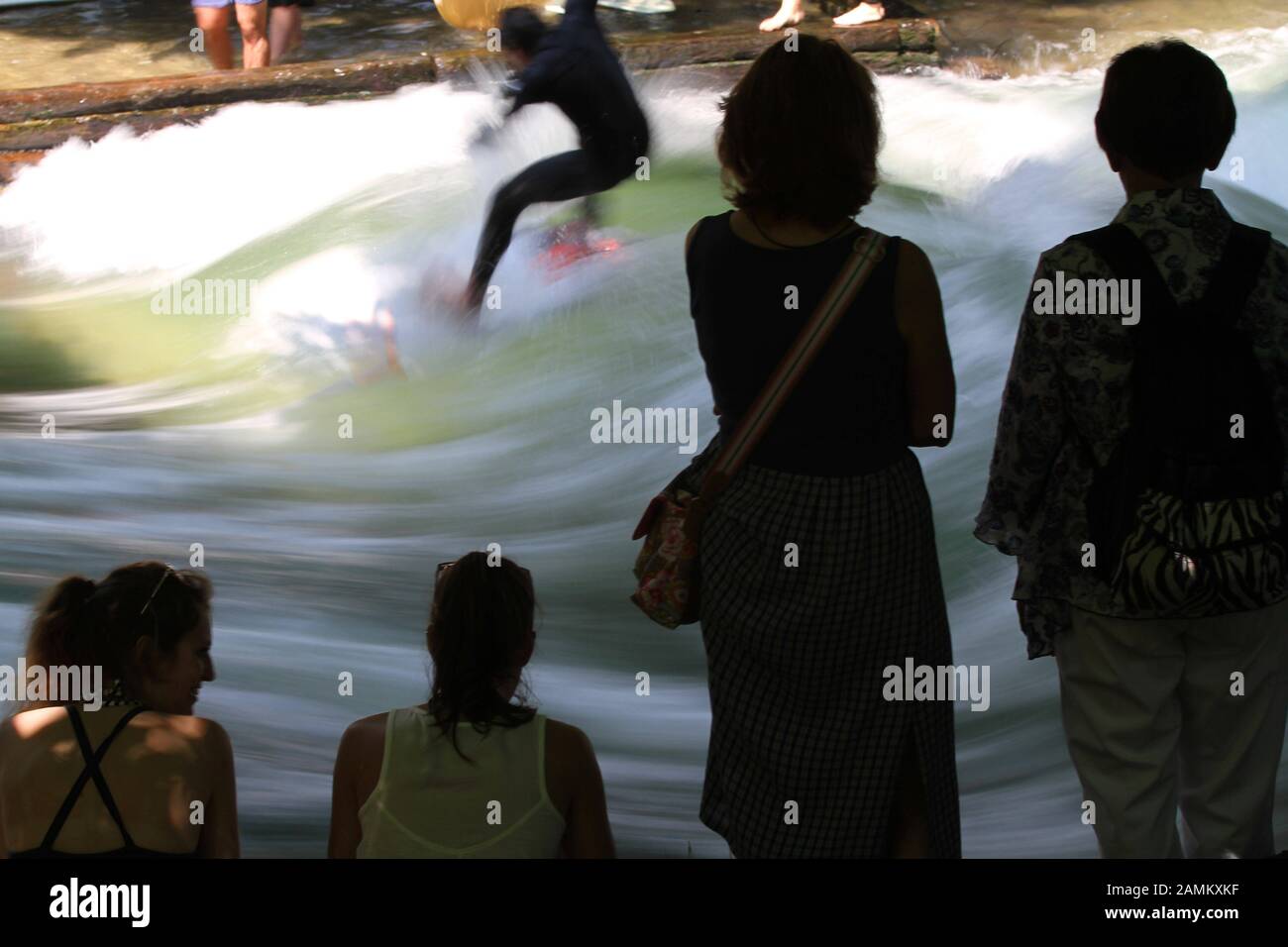 I turisti guardano i surfisti in estate all'Eisbach nel Giardino Inglese. [traduzione automatizzata] Foto Stock