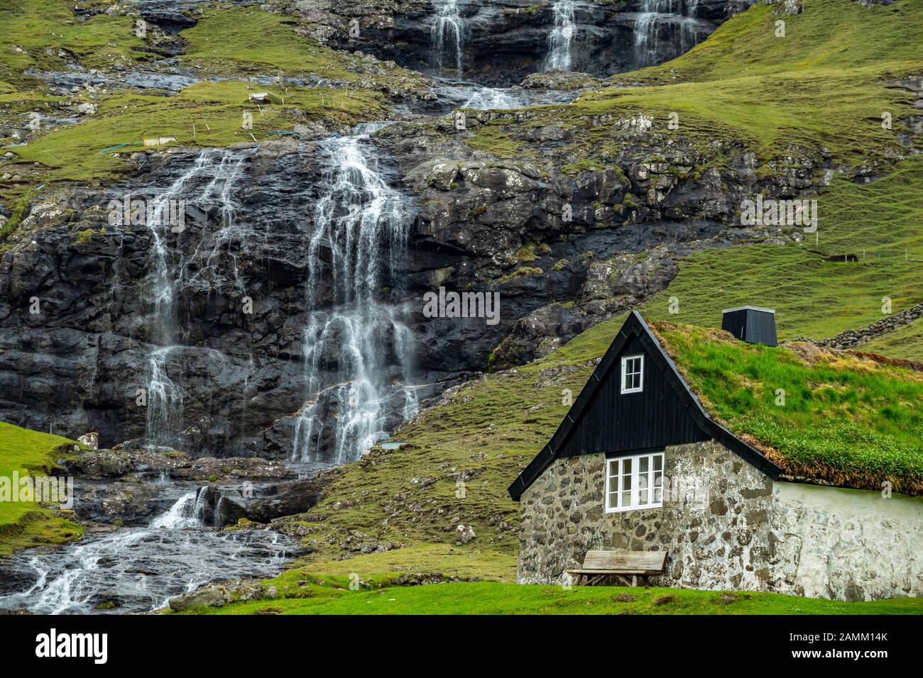 Tipica casa delle Isole Faroe sotto la cascata Foto Stock
