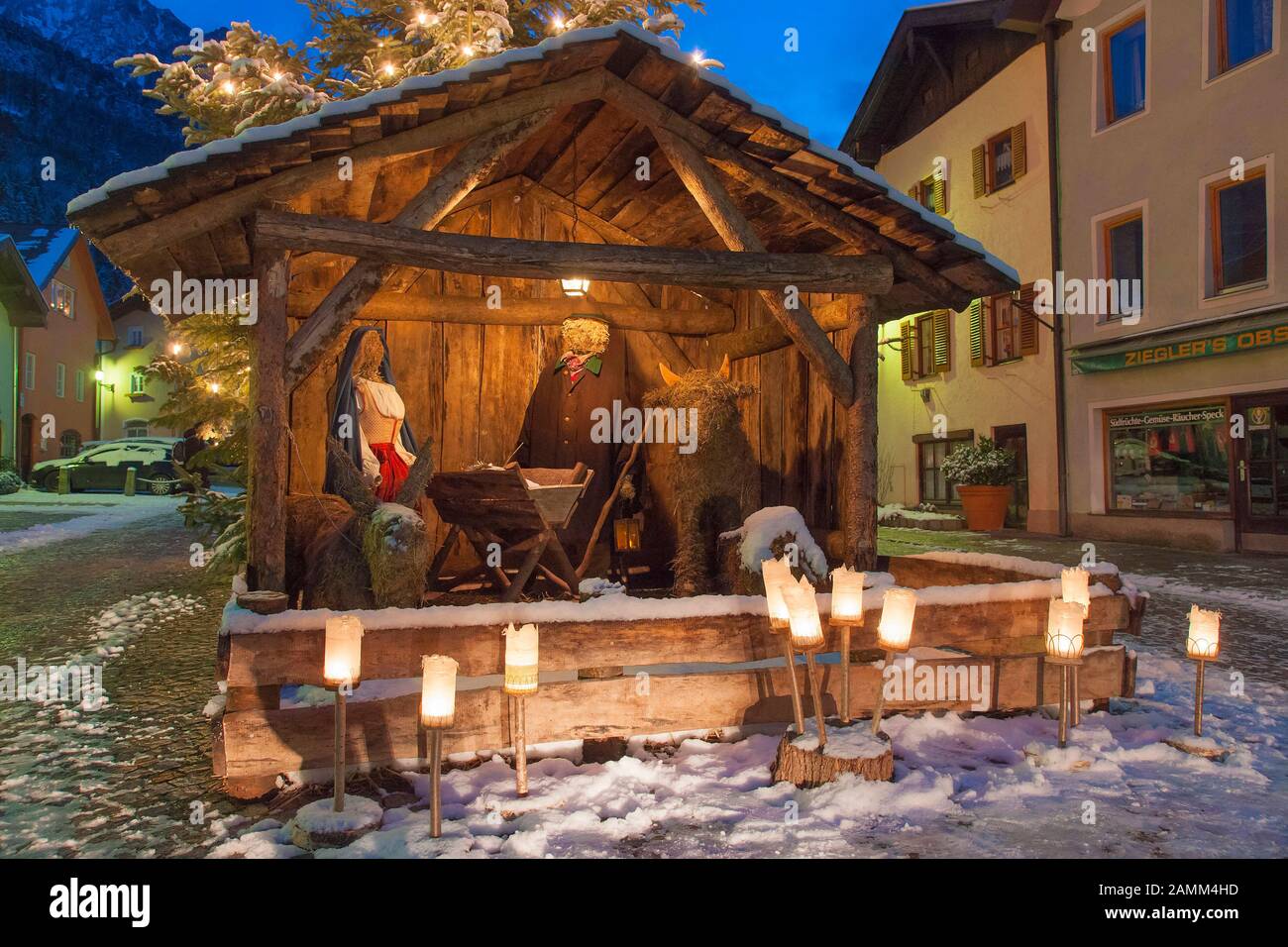 Meraviglioso presepe di natale con figure di fieno a grandezza naturale sulla neve invernale Florianiplatz a Bad Reichenhall con la sedia sermone sullo sfondo all'ora blu, uno dei quartieri più antichi di Bad Reichenhall in Berchtesgadener Land, Baviera, alta Baviera, Germania [traduzione automatizzata] Foto Stock
