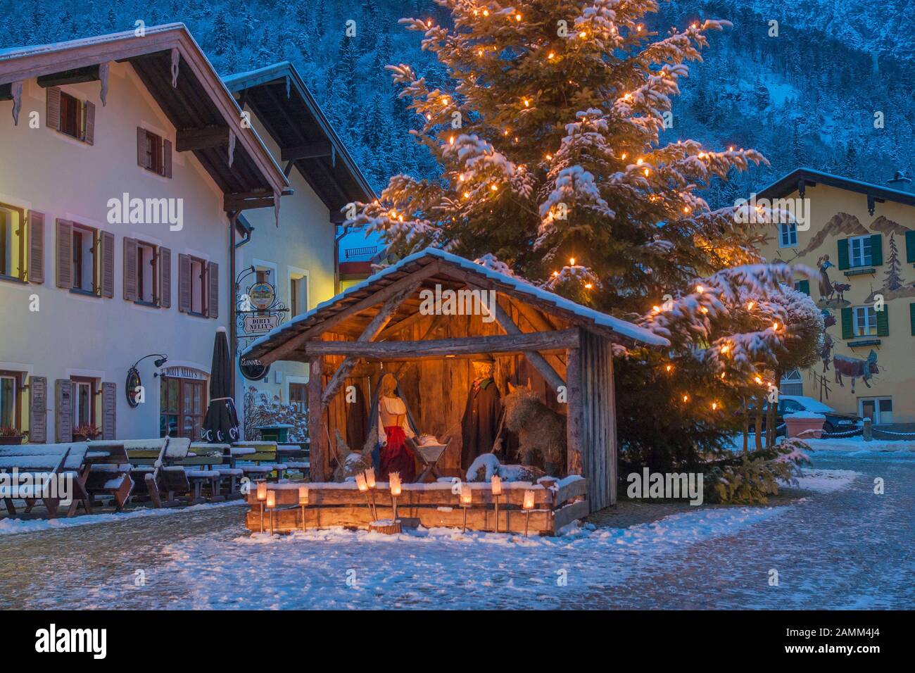 Meraviglioso presepe di natale con figure di fieno a grandezza naturale sulla neve invernale Florianiplatz a Bad Reichenhall con la sedia sermone sullo sfondo all'ora blu, uno dei quartieri più antichi di Bad Reichenhall in Berchtesgadener Land, Baviera, alta Baviera, Germania [traduzione automatizzata] Foto Stock