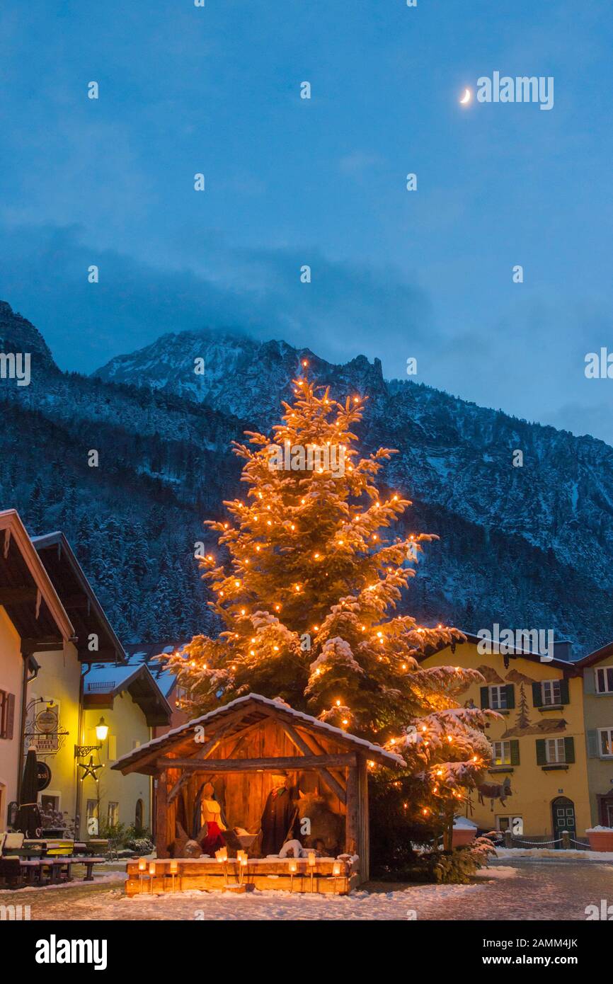 Meraviglioso presepe di natale con figure di fieno a grandezza naturale sulla neve invernale Florianiplatz a Bad Reichenhall con la sedia sermone sullo sfondo all'ora blu, uno dei quartieri più antichi di Bad Reichenhall in Berchtesgadener Land, Baviera, alta Baviera, Germania [traduzione automatizzata] Foto Stock