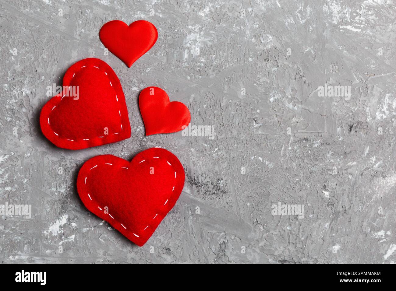 Vista dall'alto composizione dei cuori rossi su sfondo cementizio. Concetto di relazione romantica. Il giorno di Valentaine. Foto Stock